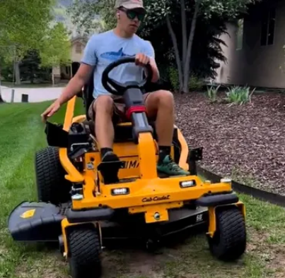 Operator using a zero-turn mower on turf